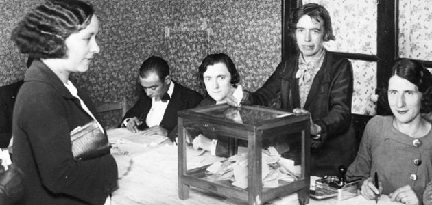 Fotagrafia en blanco y negro de una fila de mujeres pidiendo el voto para la mujer