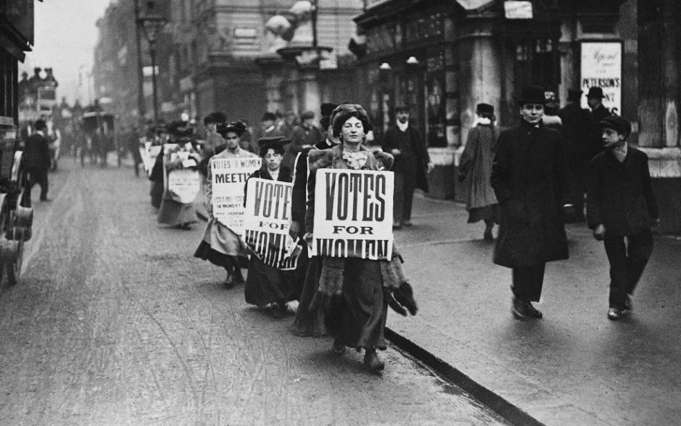 Fotagrafia en blanco y negro de una fila de mujeres pidiendo el voto para la mujer